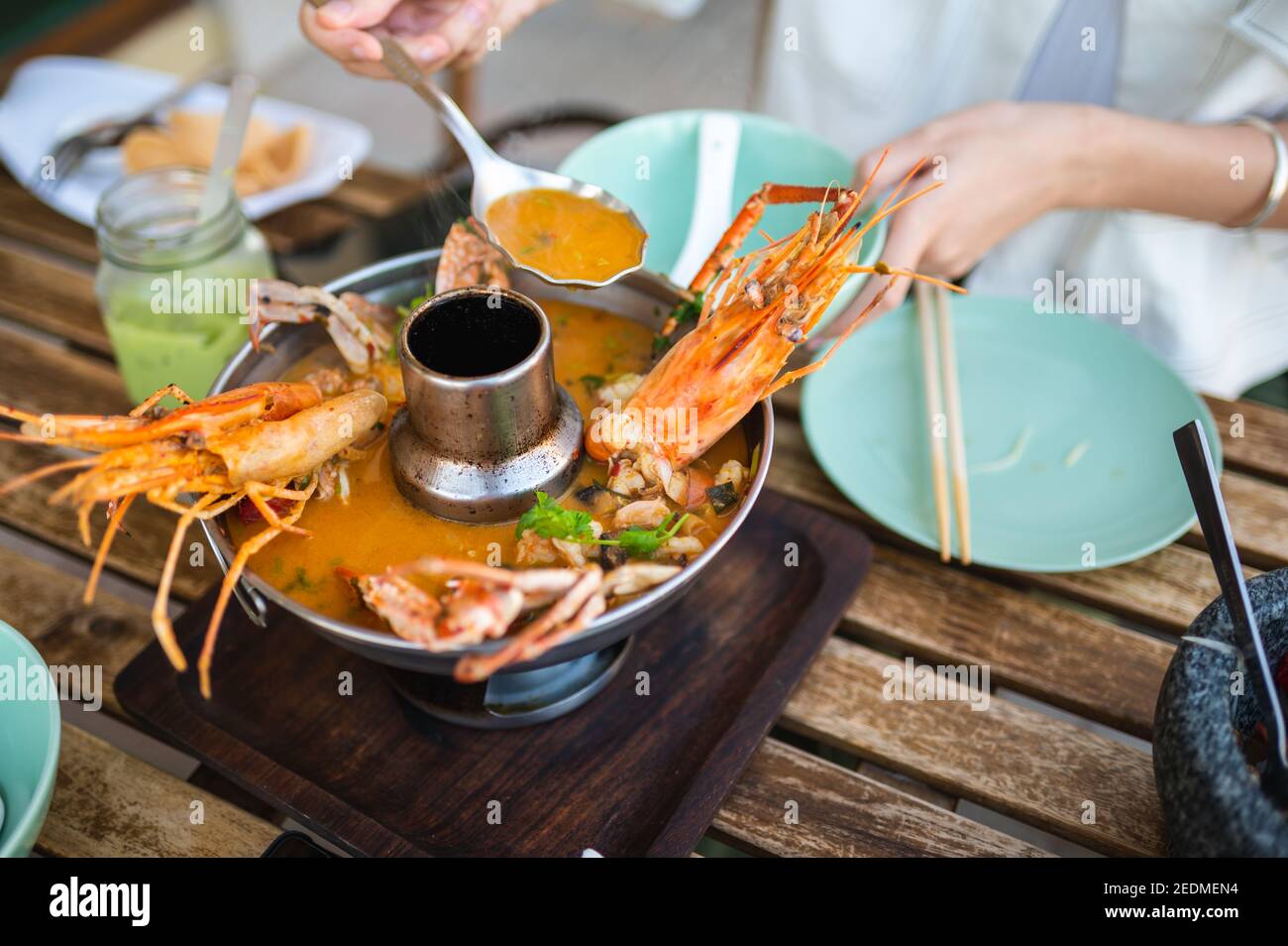 Woman having Thai Tom Yum soup with prawns and crab in a restaurant Stock Photo