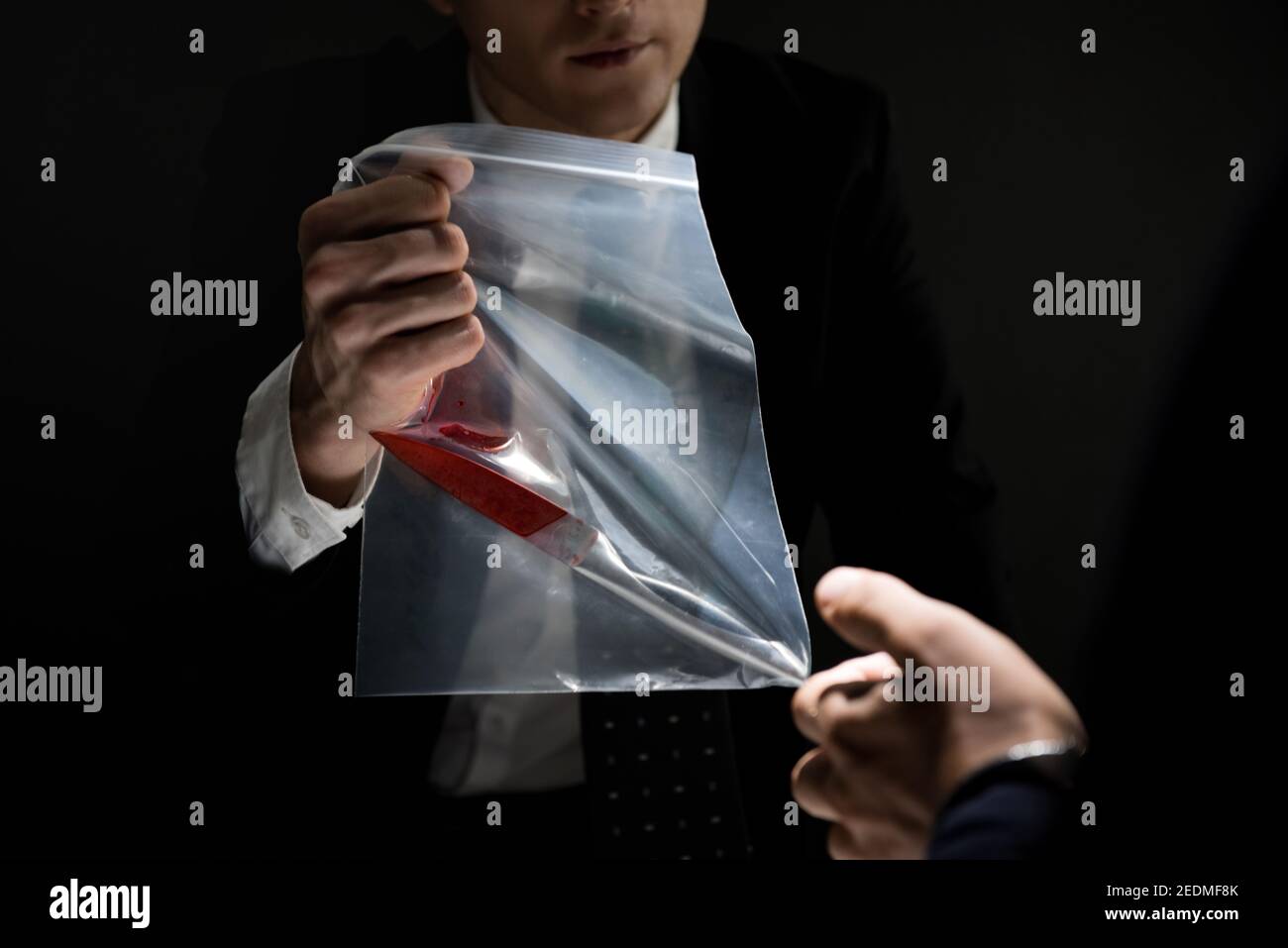 Detective showing a knife with blood as an evidence in crime investigation Stock Photo