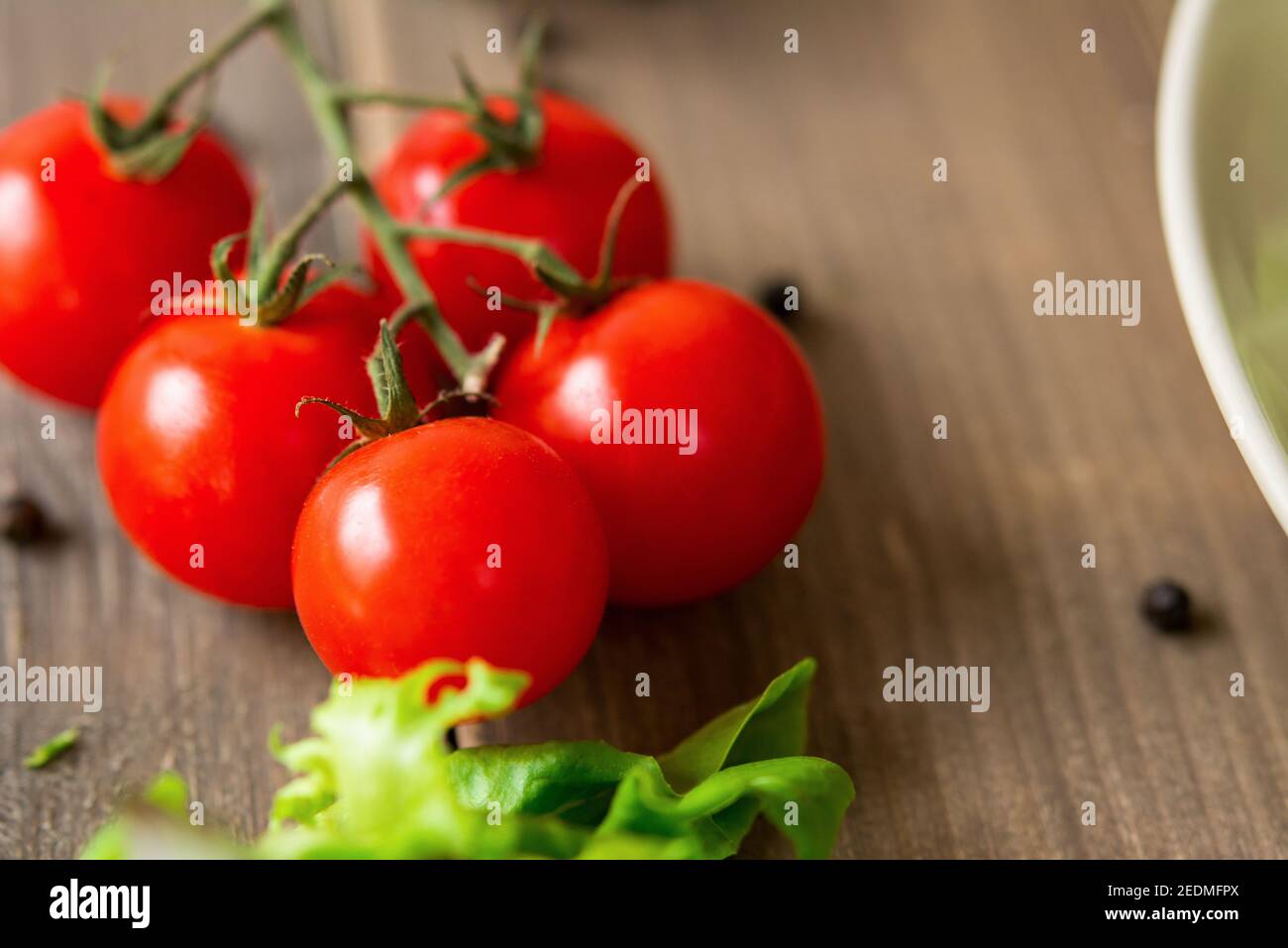 Organic healthy red cherry tomato bunch for salad on wood table, closed up shot Stock Photo