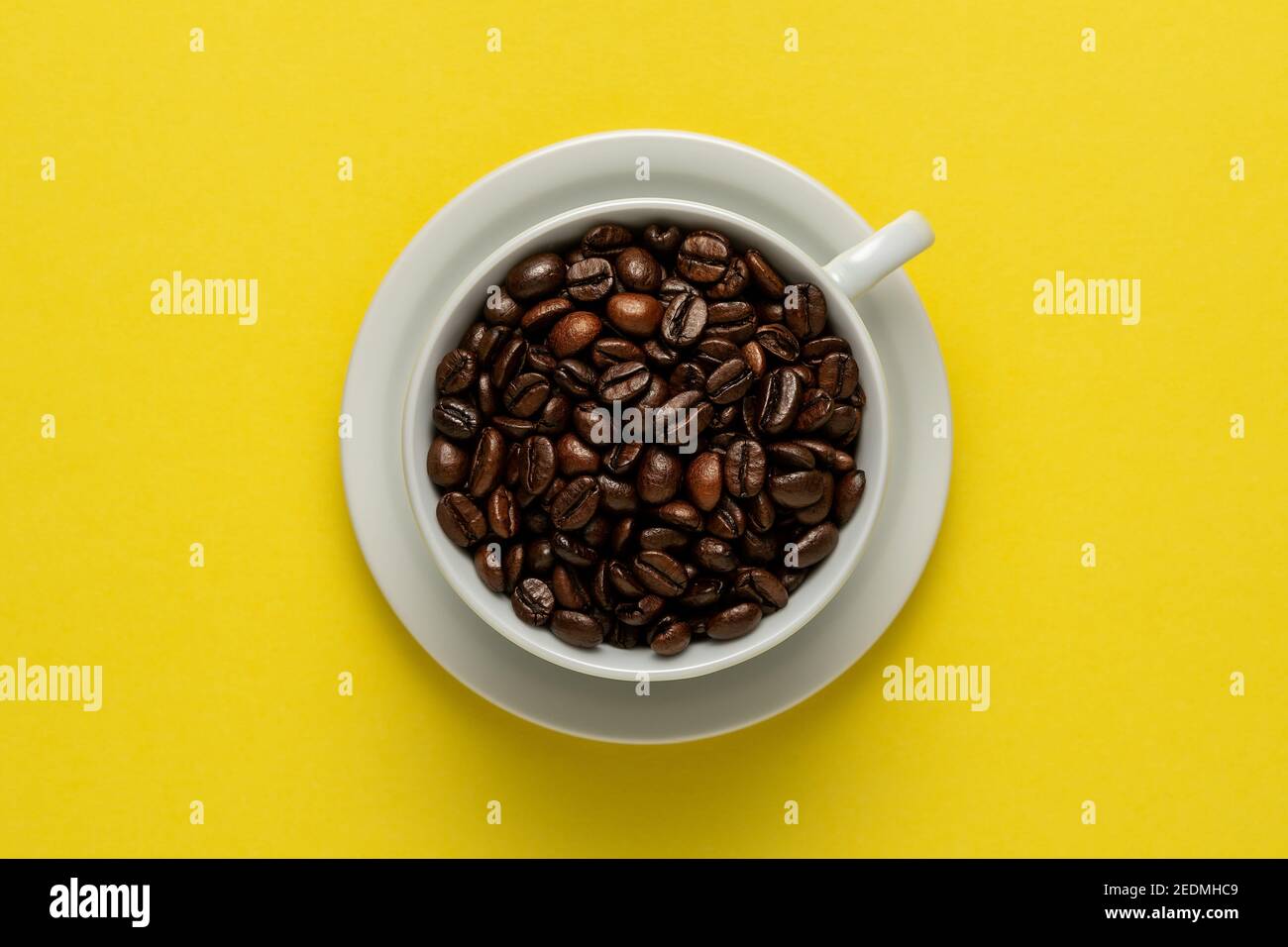 Cup of coffee with coffee beans on yellow background. Creative minimal coffee drink concept. Stock Photo