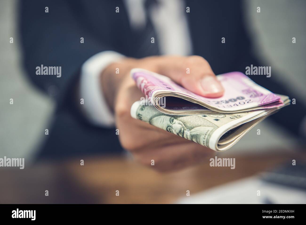 Businessman giving money in the form of Indian Rupees currency for services rendered Stock Photo