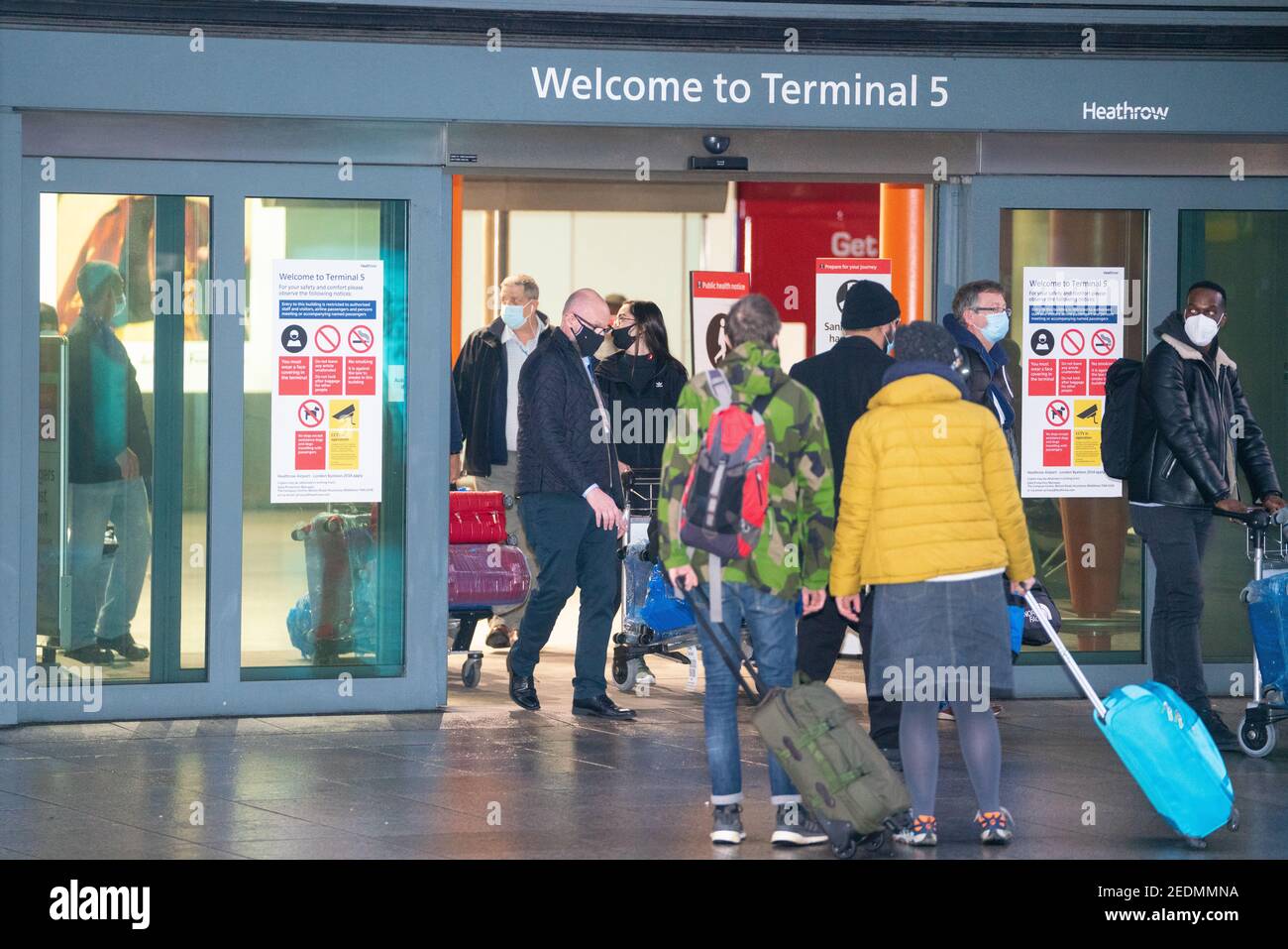 Passengers are escorted from London Heathrow's Terminal 5 past other members of the public after arriving on the first flight to the airport from one of 33 'red list' countries to which new mandatory coronavirus rules apply. Picture date: Monday February 15, 2021. Stock Photo