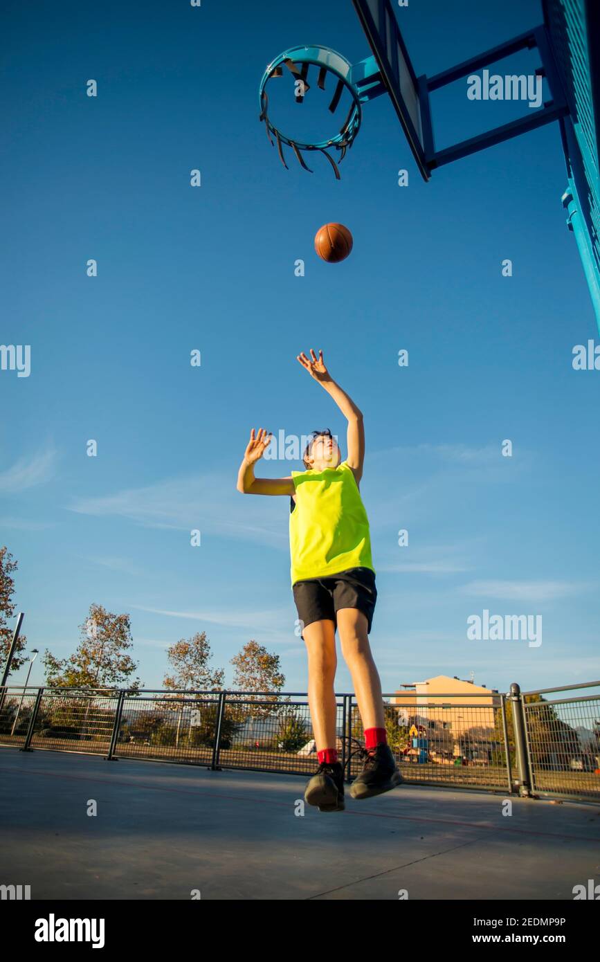 teenager throwing a basketball into the hoop from behind Stock Photo