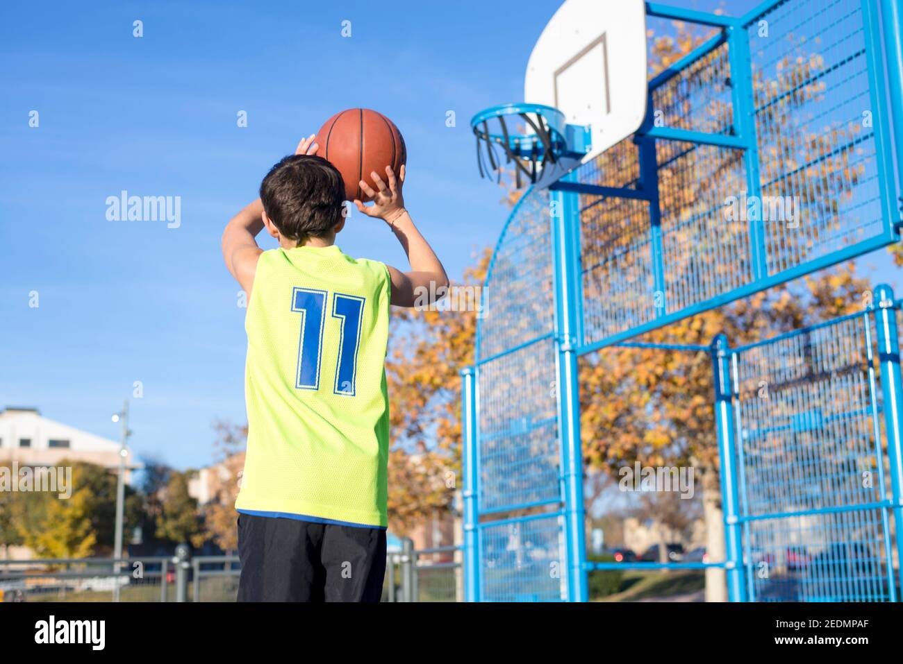 teenager throwing a basketball into the hoop from behind Stock Photo