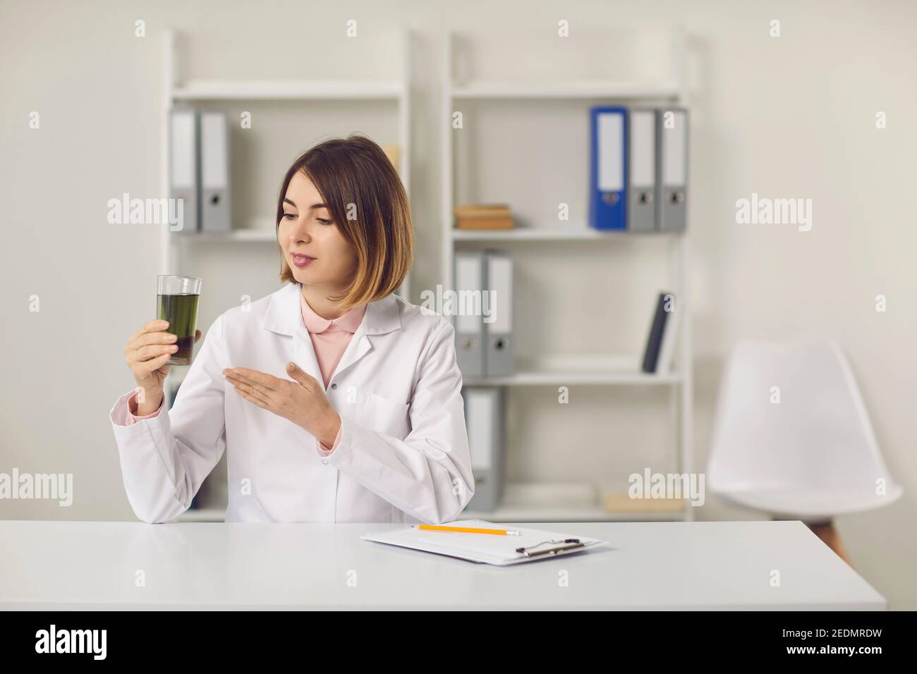 Dietitian sitting at desk in clinic office and telling about benefits of detox drink Stock Photo