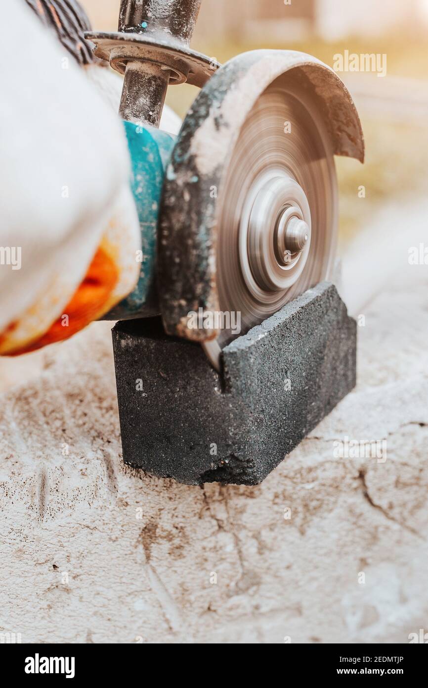 Sawing concrete stone with a diamond blade on an electric grinder - powerful stone cutter Stock Photo