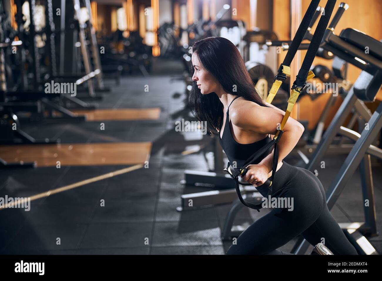 Motivated slim woman doing suspension workout in gym Stock Photo