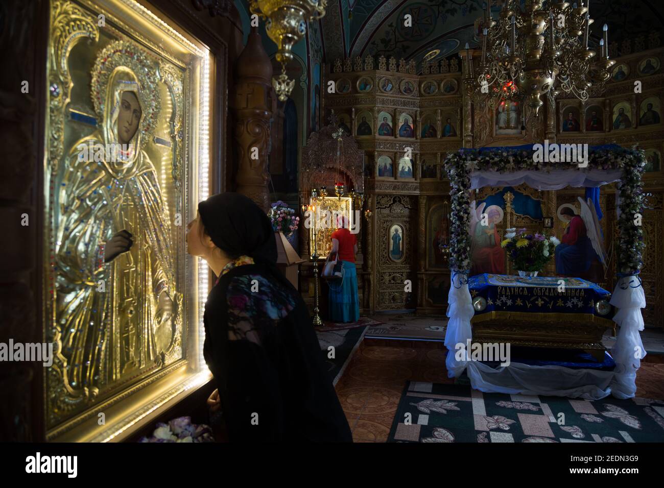 02.09.2016, , Rajon Rezina, Moldova - Nun kissing an icon, behind the iconostasis at Trinity Monastery Saharna.. 00A160902D105CAROEX.JPG [MODEL RELEAS Stock Photo
