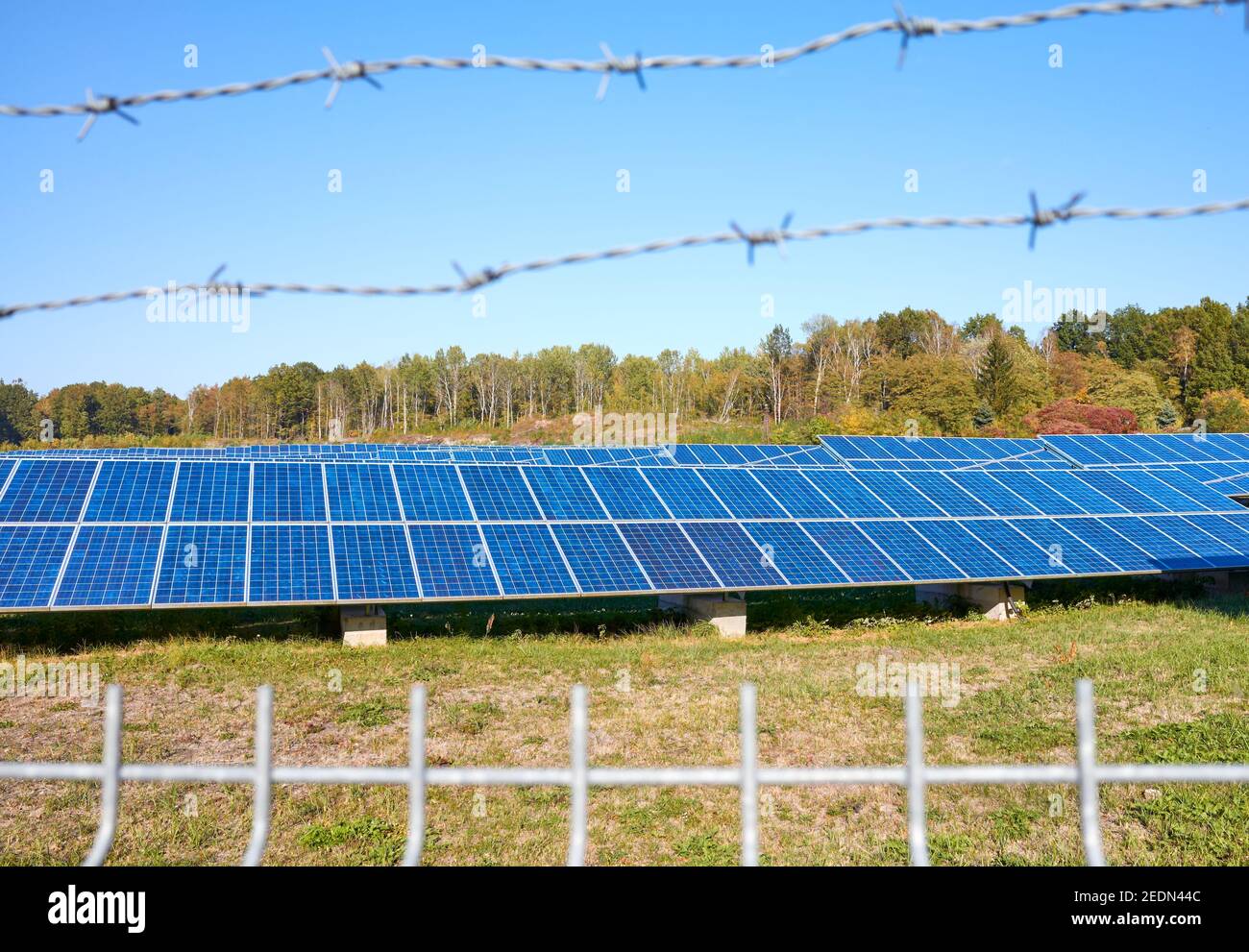 Solar panels behind barbed wired fence, selective focus. Stock Photo