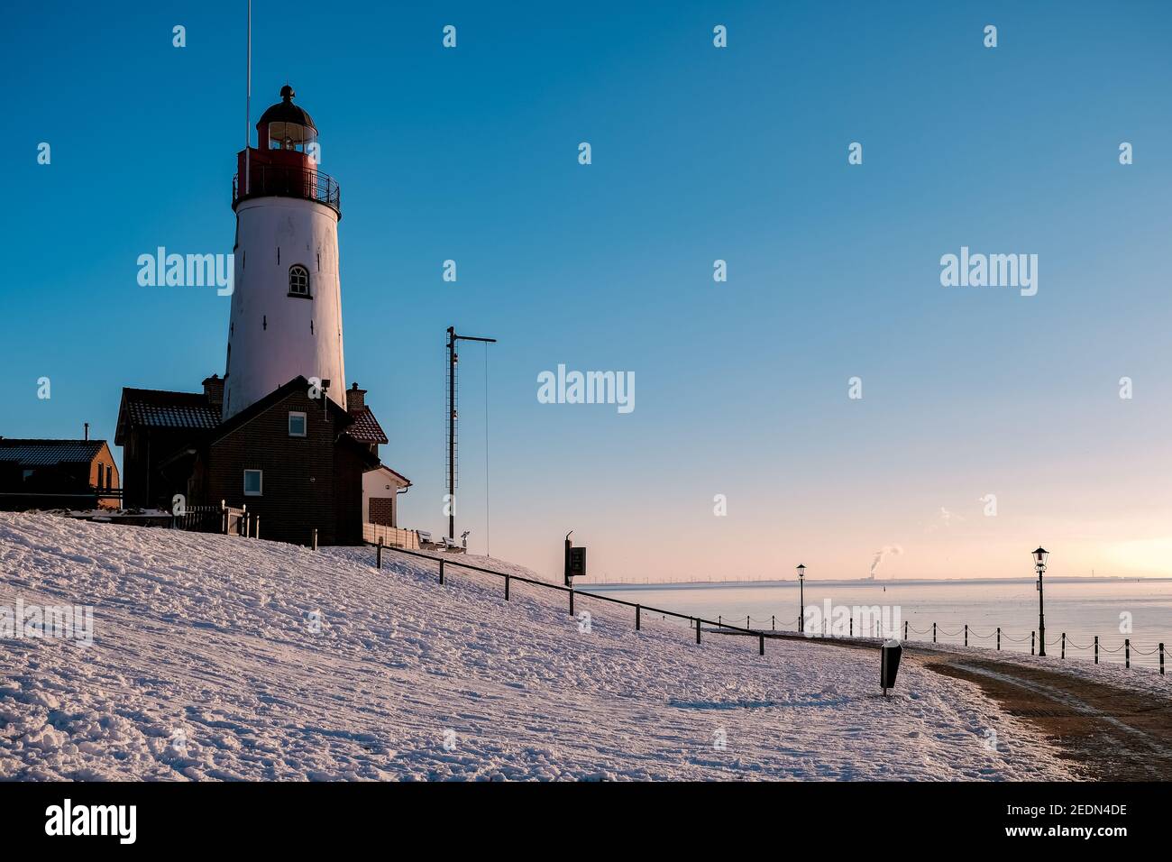 snow covered beach during wnter by Urk lighthouse in the Netherlands