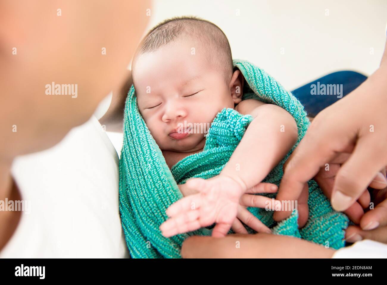 Adorable newborn little baby sleeping in the arms of father Stock Photo