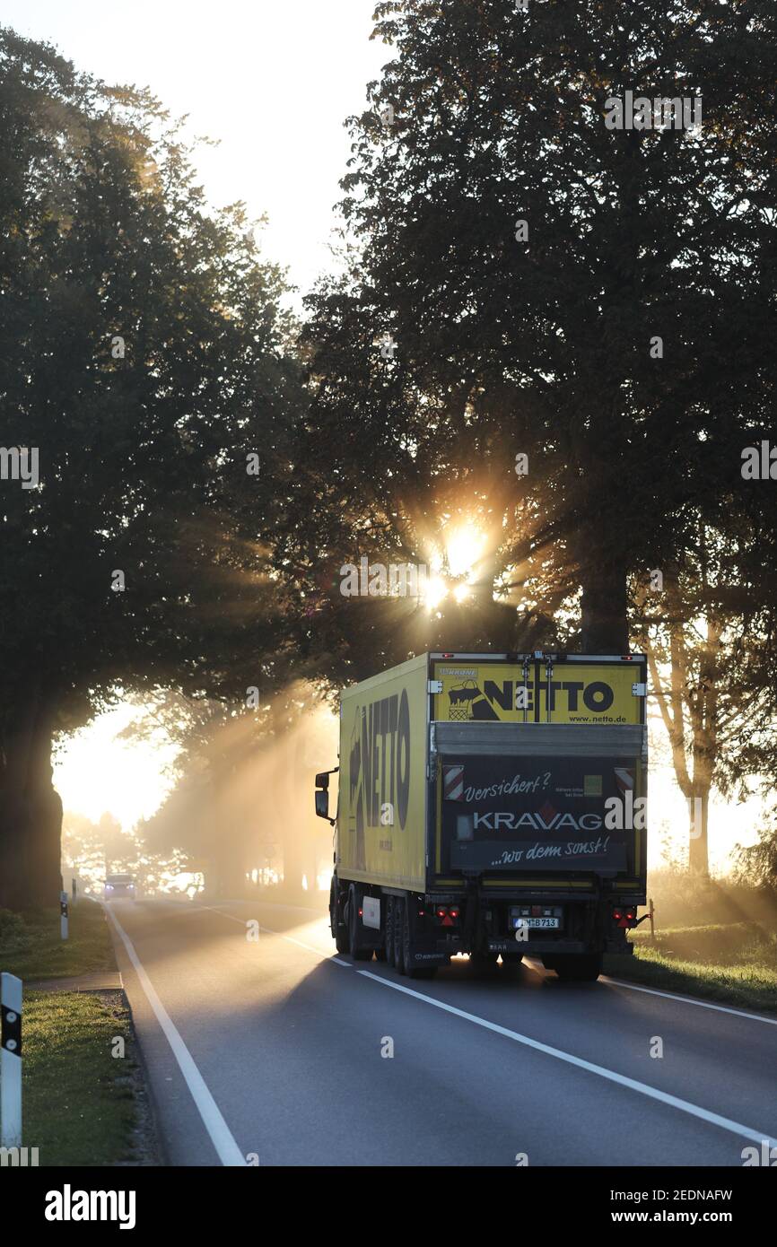 17.10.2020, Neu Heinde, Mecklenburg-Western Pomerania, Germany - A lorry of the grocery store Netto is driving on a country road at sunrise.. 00S20101 Stock Photo