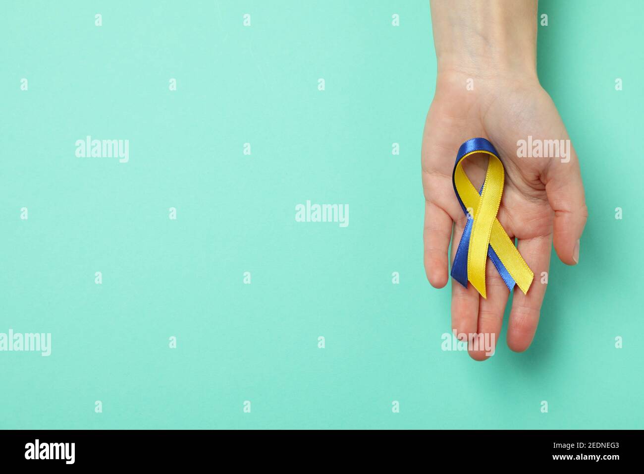Female hands hold Down's syndrome awareness ribbons on mint background