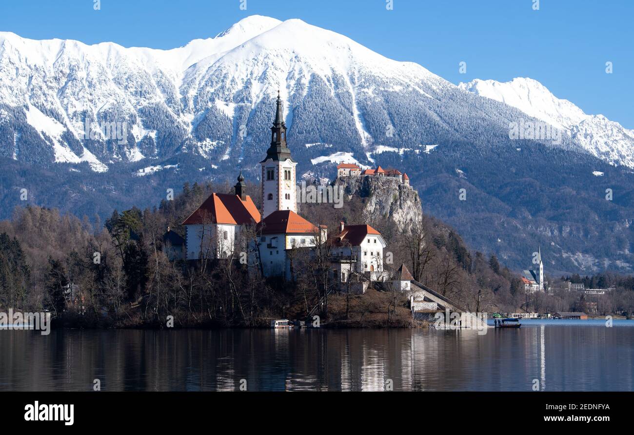 Bled, Slovenia. 15th Feb, 2021. The Church of the Assumption of the Virgin Mary on the island of Blejski Otok in Lake Bled at the foot of the Pokljuka plateau. Bled Castle can be seen in the background. Pokljuka will host the Biathlon World Championships from 10-21 February 2021. Credit: Sven Hoppe/dpa/Alamy Live News Stock Photo