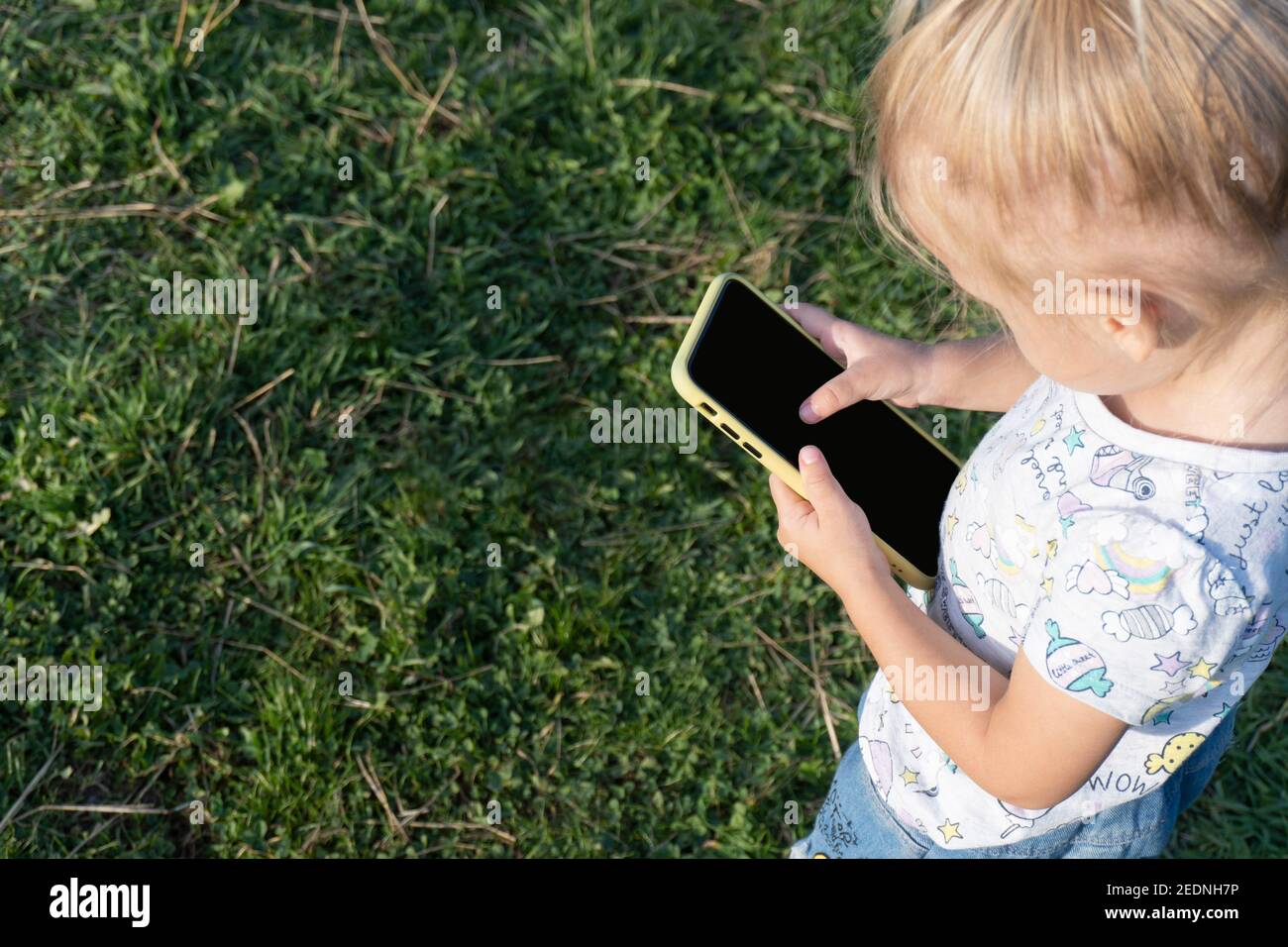 Kid skrolling at mobile phone with big finger Stock Photo