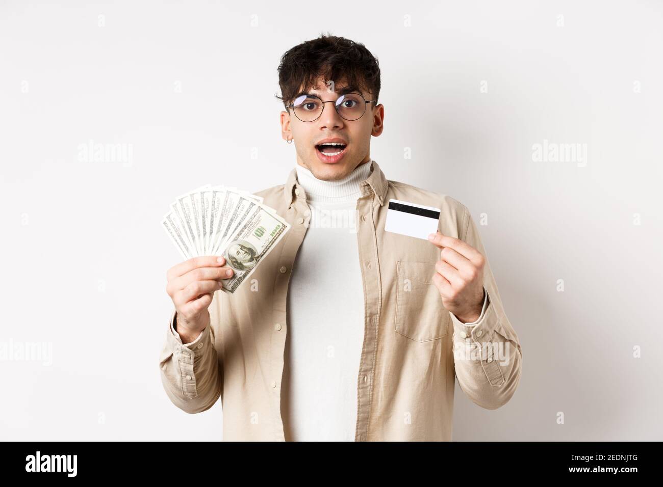 Excited young guy showing dollar bills and credit card, earn money and