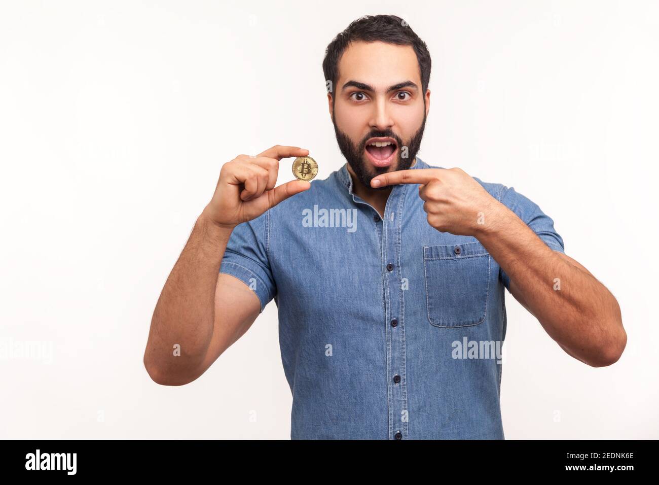 Surprised bearded man pointing finger at golden bitcoin cryptocurrency,  looking at camera with astonishment, shocked with price. Indoor studio shot  is Stock Photo - Alamy