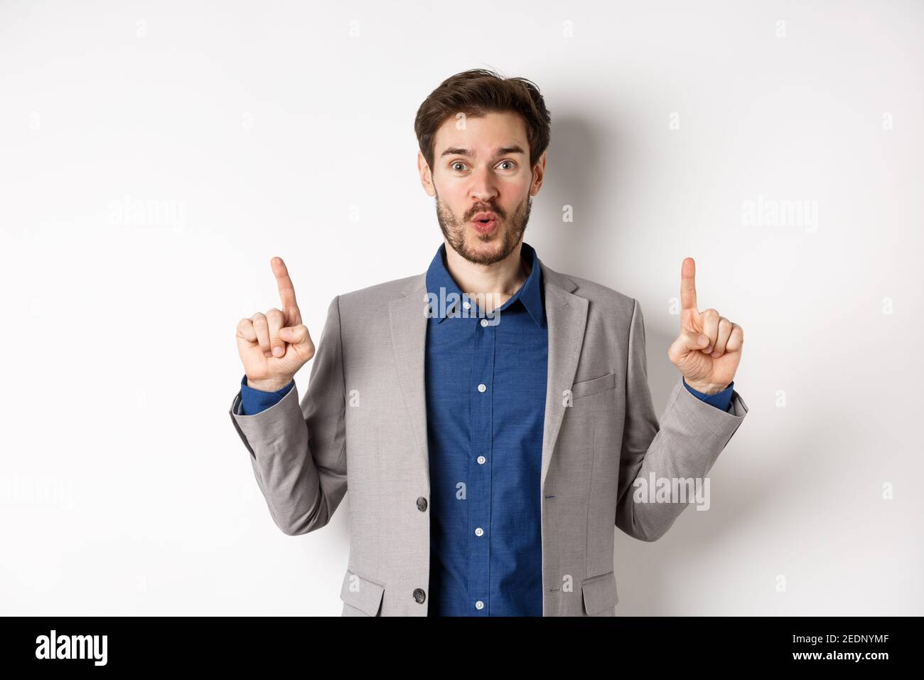 Excited businessman in suit say wow and smiling amused, pointing fingers up  at good deal, standing against white background Stock Photo - Alamy