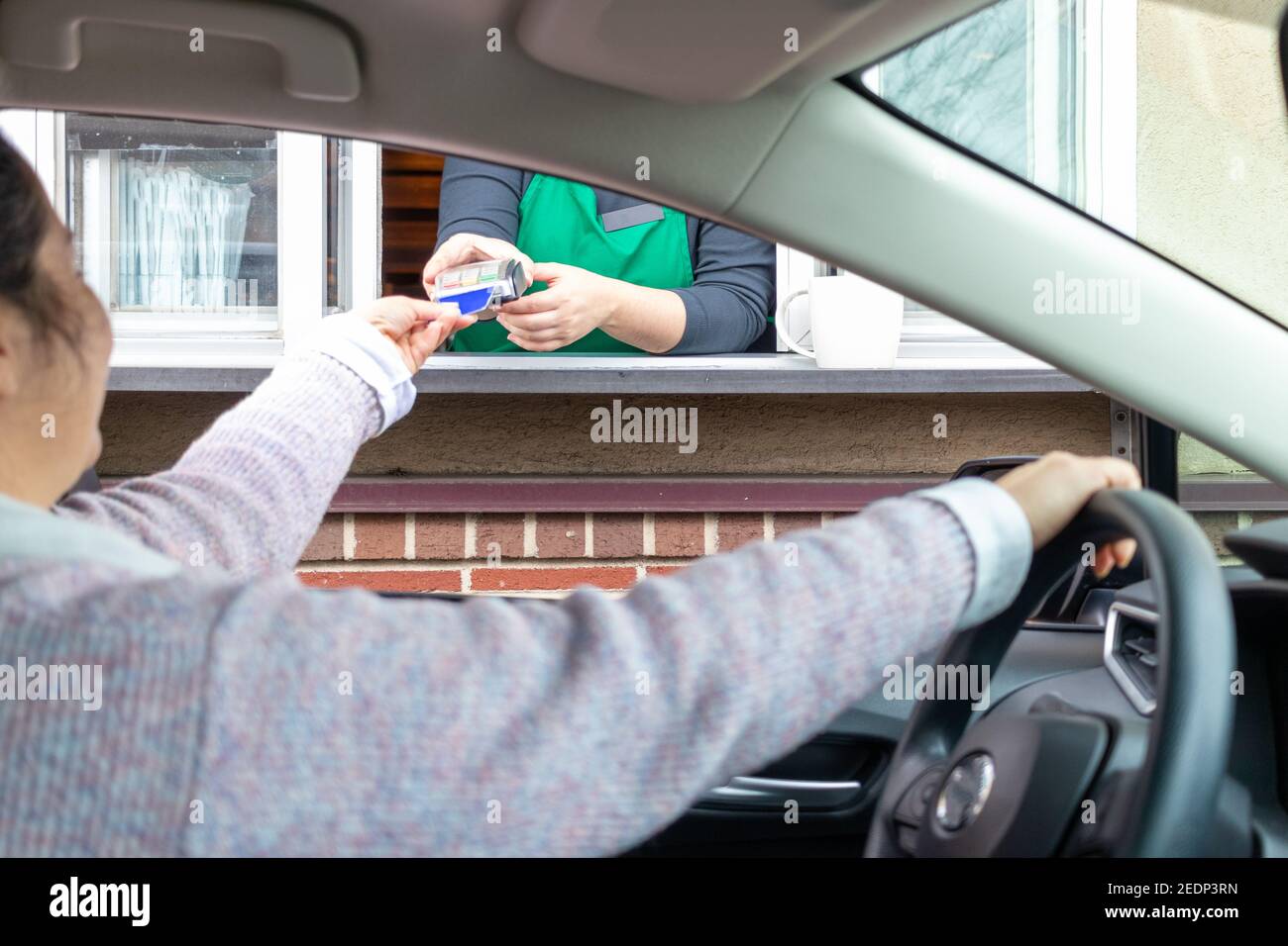 Young woman pays for service through Drive thru Stock Photo