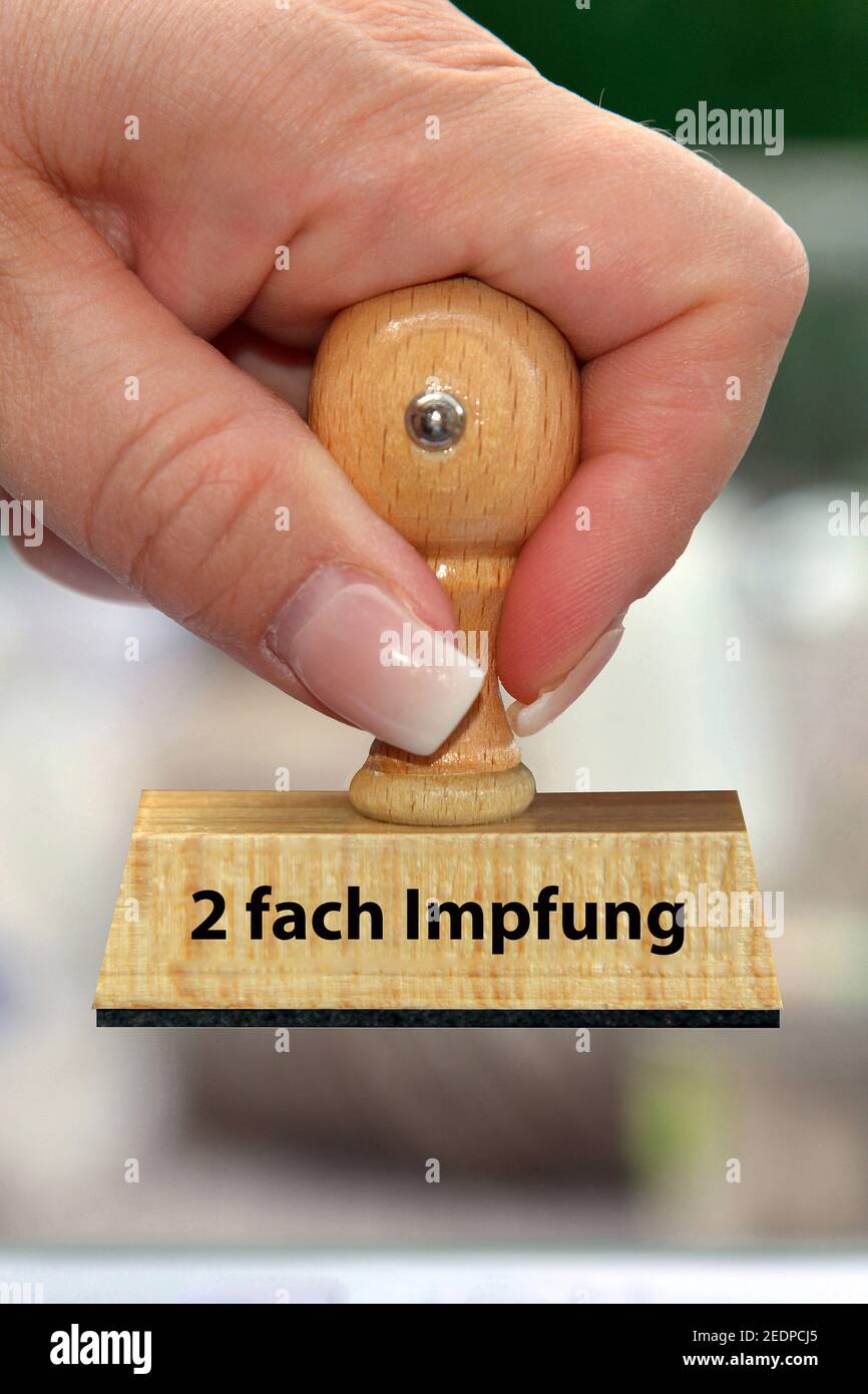 woman's hand with stamp lettering 2-fach Impfung, two-time inoculation, Germany Stock Photo