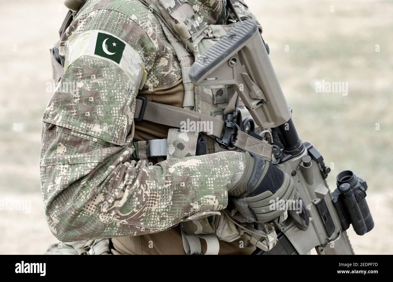 Soldier with machine gun and flag of Pakistan on military uniform