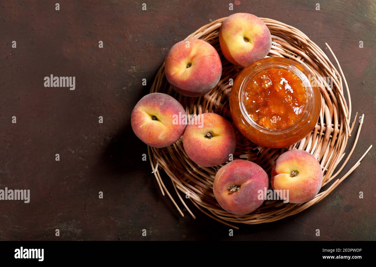 glass jar of peach jam with fresh fruits on a old table, top view Stock