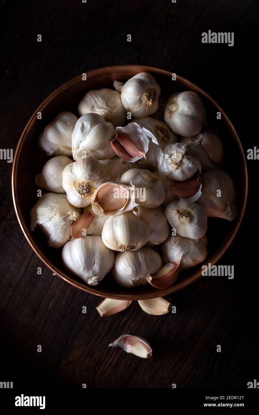 Garlic Cloves and Bulb in metal bowl on dark wooden background Stock ...