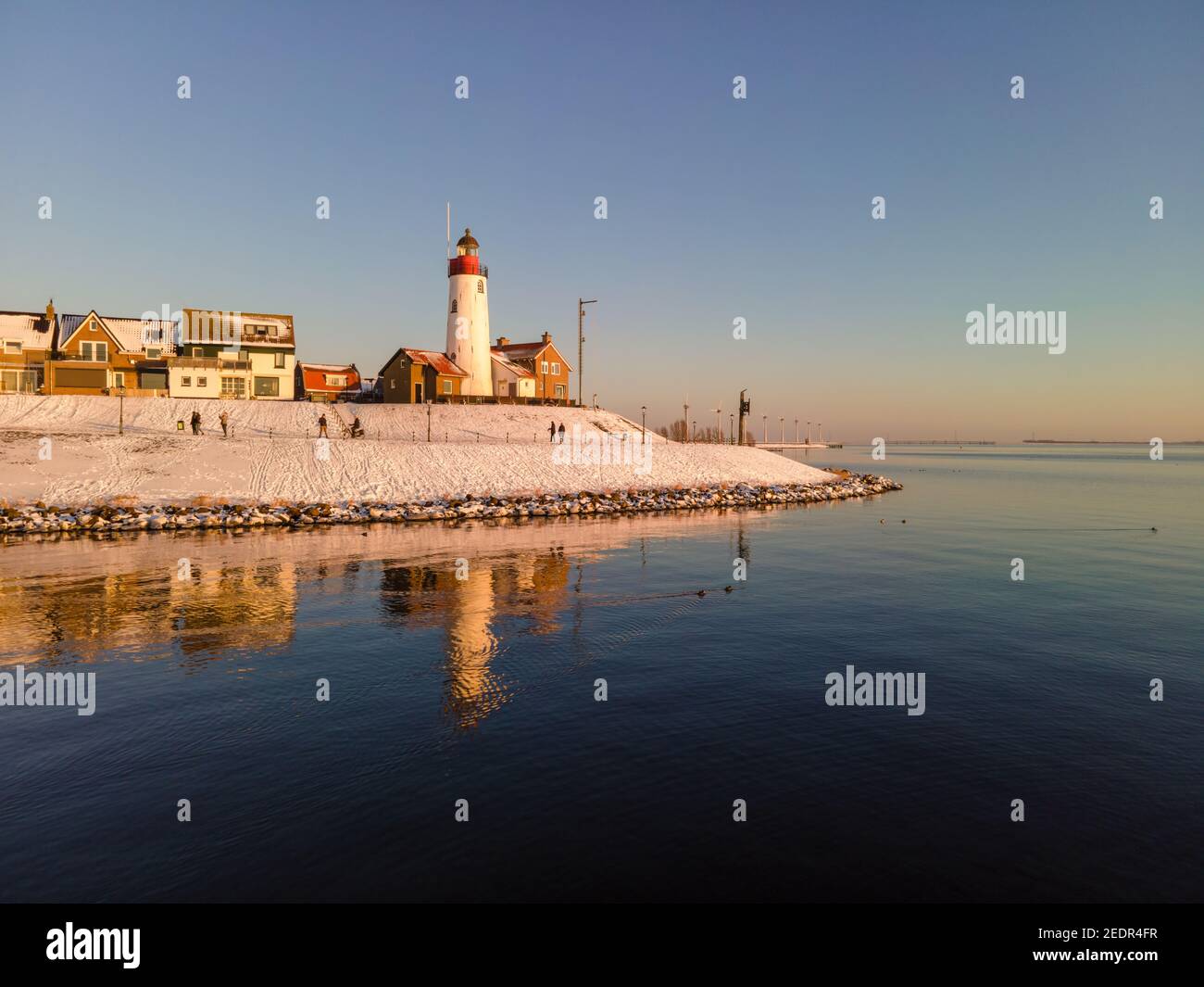 snow covered beach during wnter by Urk lighthouse in the Netherlands