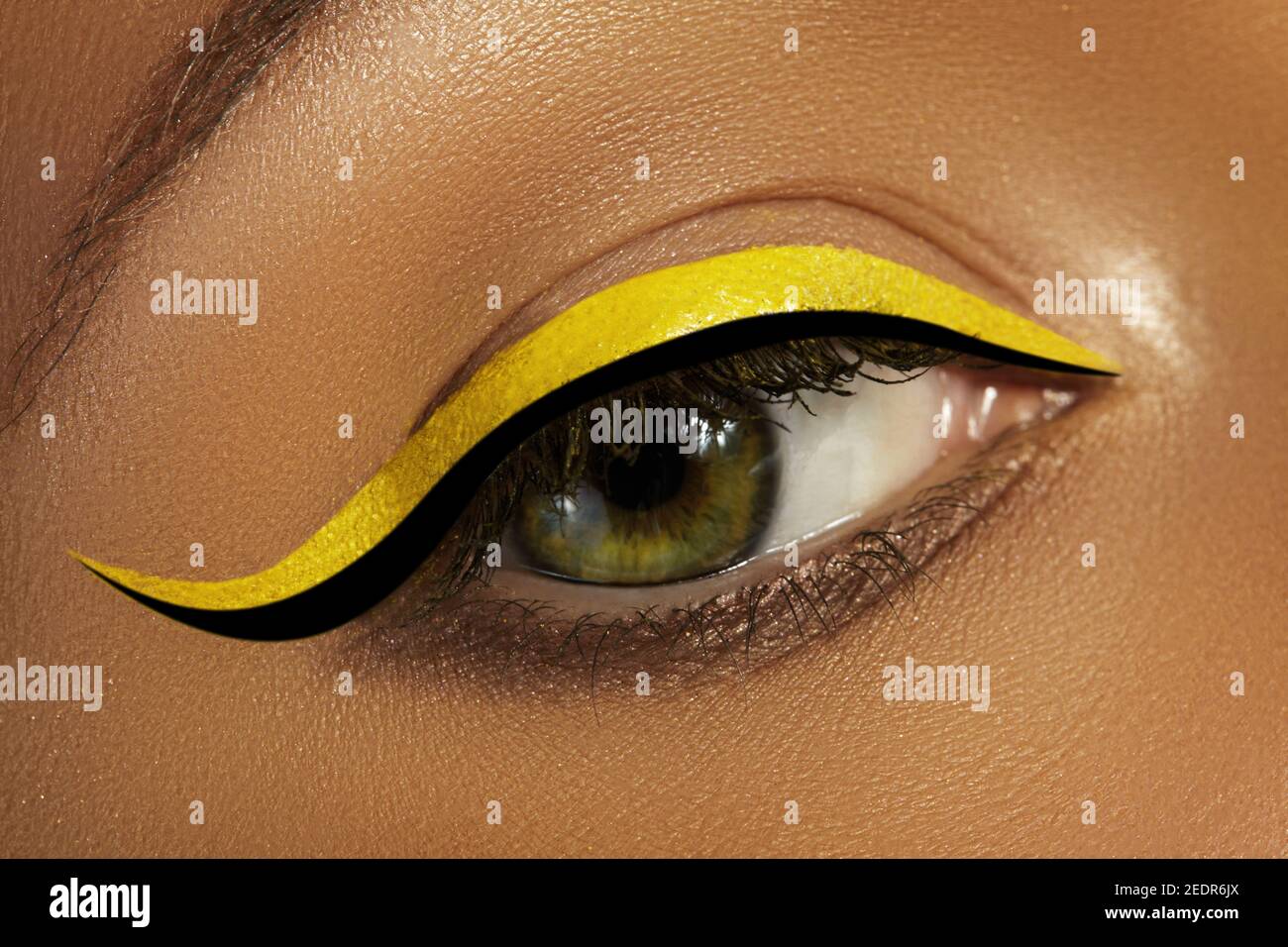 Beautiful macro close-up of female Eye with bright yellow Eyeliner Makeup. Neon Disco make-up with fashion black liner. Summer beauty style. Closeup m Stock Photo