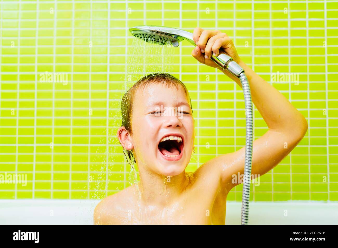 Handsome boy washes his head with water dripping down his face in the