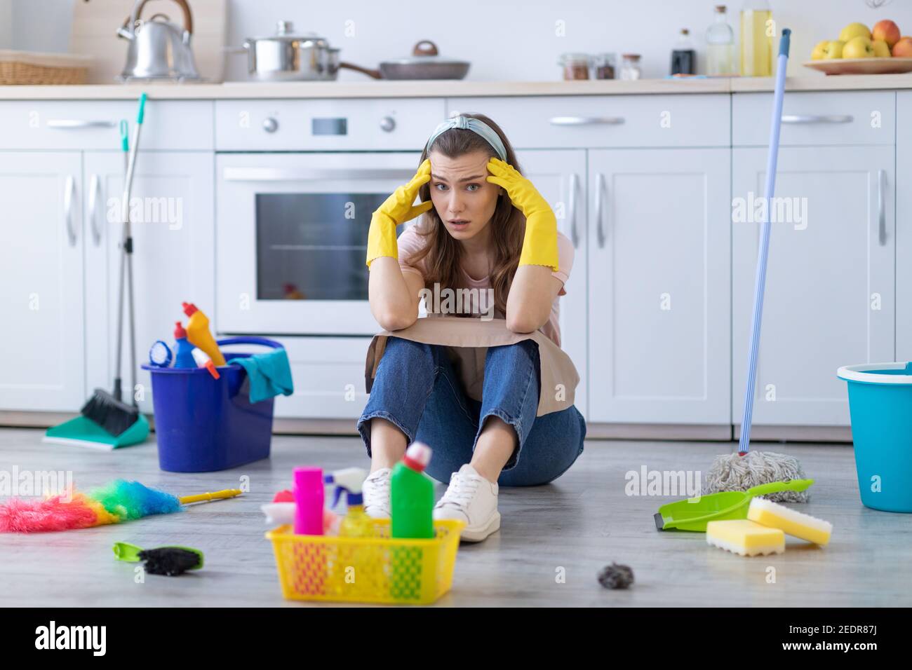 Premium Photo  Tired housewife with cleaning tools is sitting on