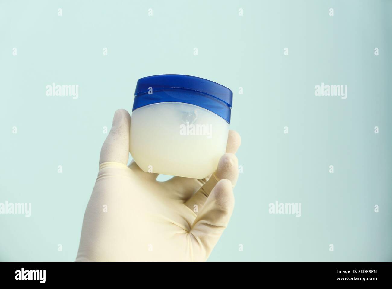 hand in latex gloves holding petroleum jelly Stock Photo Alamy