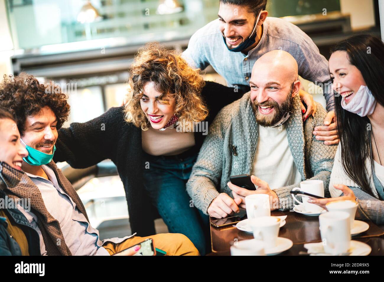 People having fun drinking cappuccino at coffeehouse - Young friends talking together at restaurant cafeteria - New normal gathering concept Stock Photo