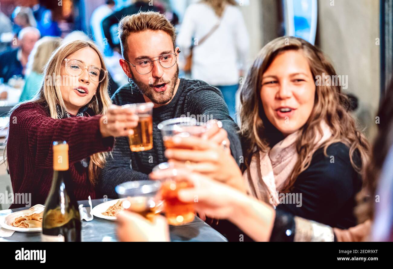 Young people having fun toasting white wine at street food festival - Happy friends eating local plates at restaurant dehor together Stock Photo