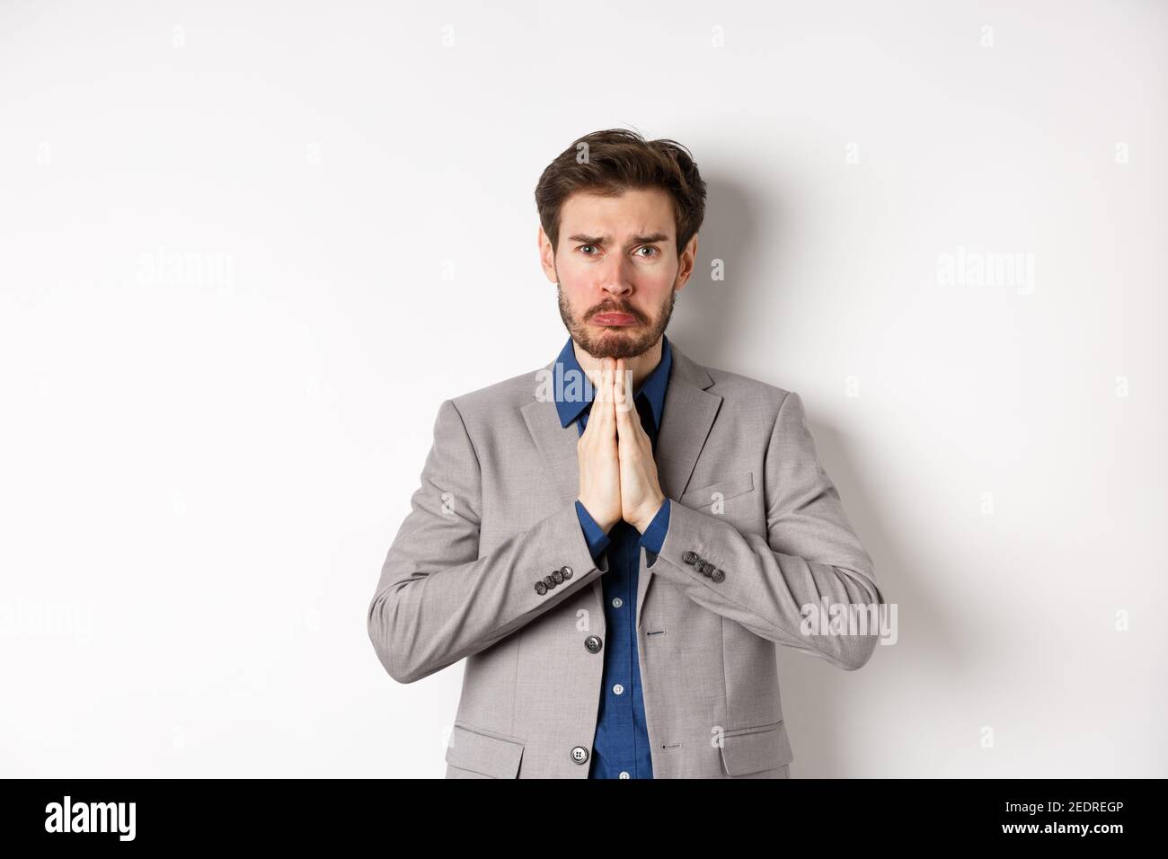 Miserable whining businessman asking for loan, need help and begging you, sobbing and say please with sad face, standing on white background, ask for Stock Photo