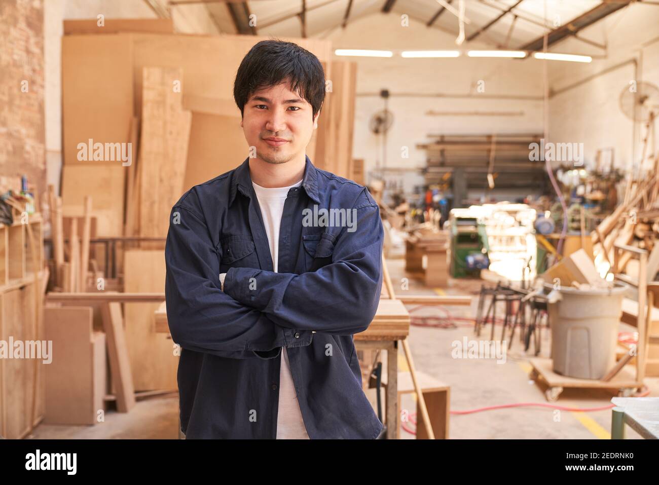 Young man with folded arms as an apprentice in the carpentry workshop Stock Photo