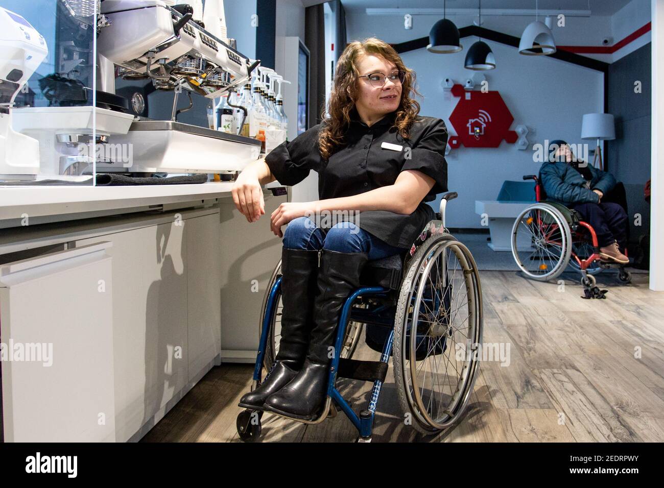 MINSK, BELARUS - January, 2021: Wheelchair disabled person works as a barista in an inclusive coffee shop. This is Natasha Astanina. She is 25 years old. She is a wheelchair user since childhood. The barista works. Has been engaged in sports dancing since the age of 13. He is fond of parachuting. On account of 10 parachute jumps. Stock Photo