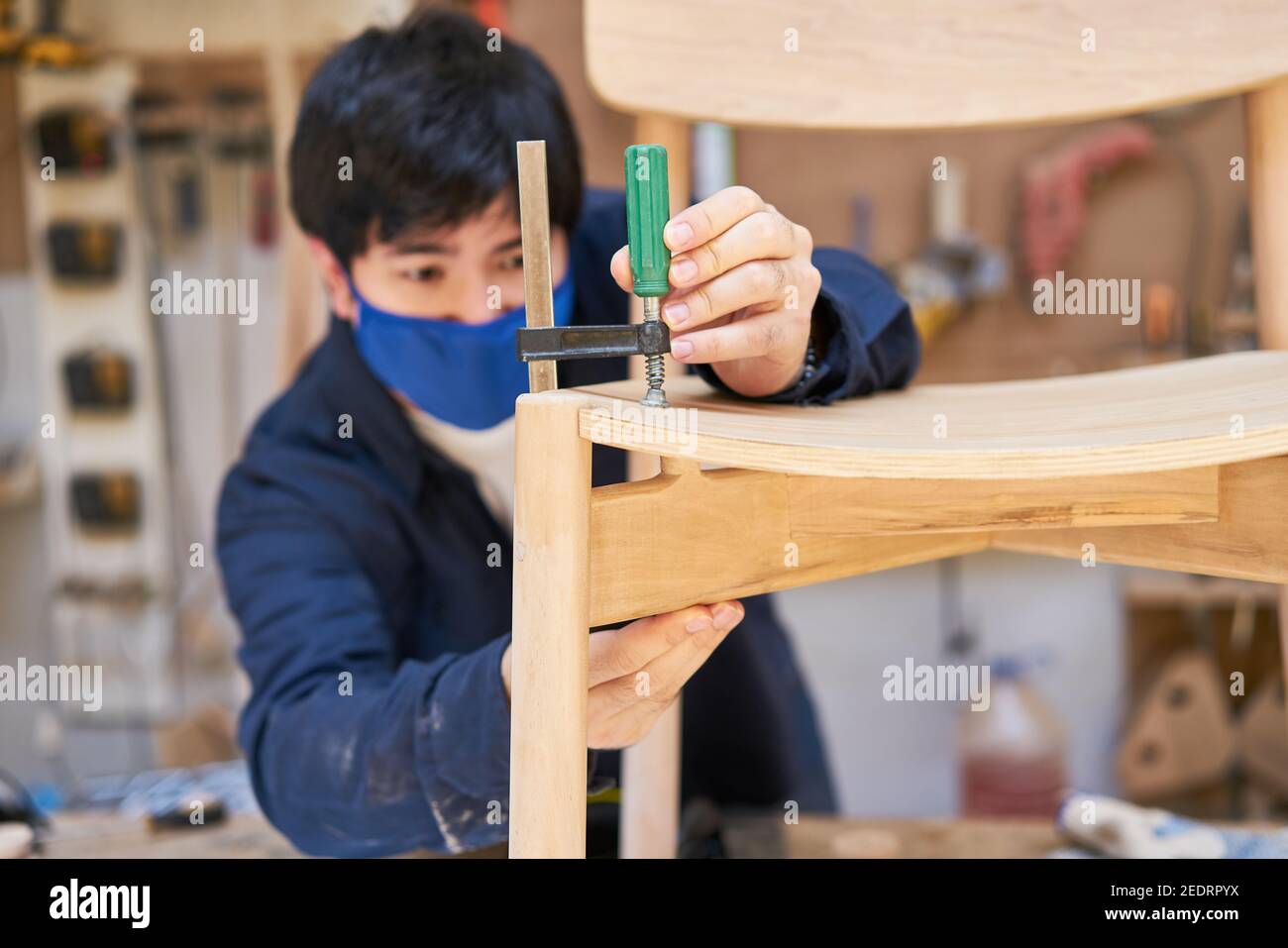 Carpenter apprentice gluing and repairing chairs in the maker