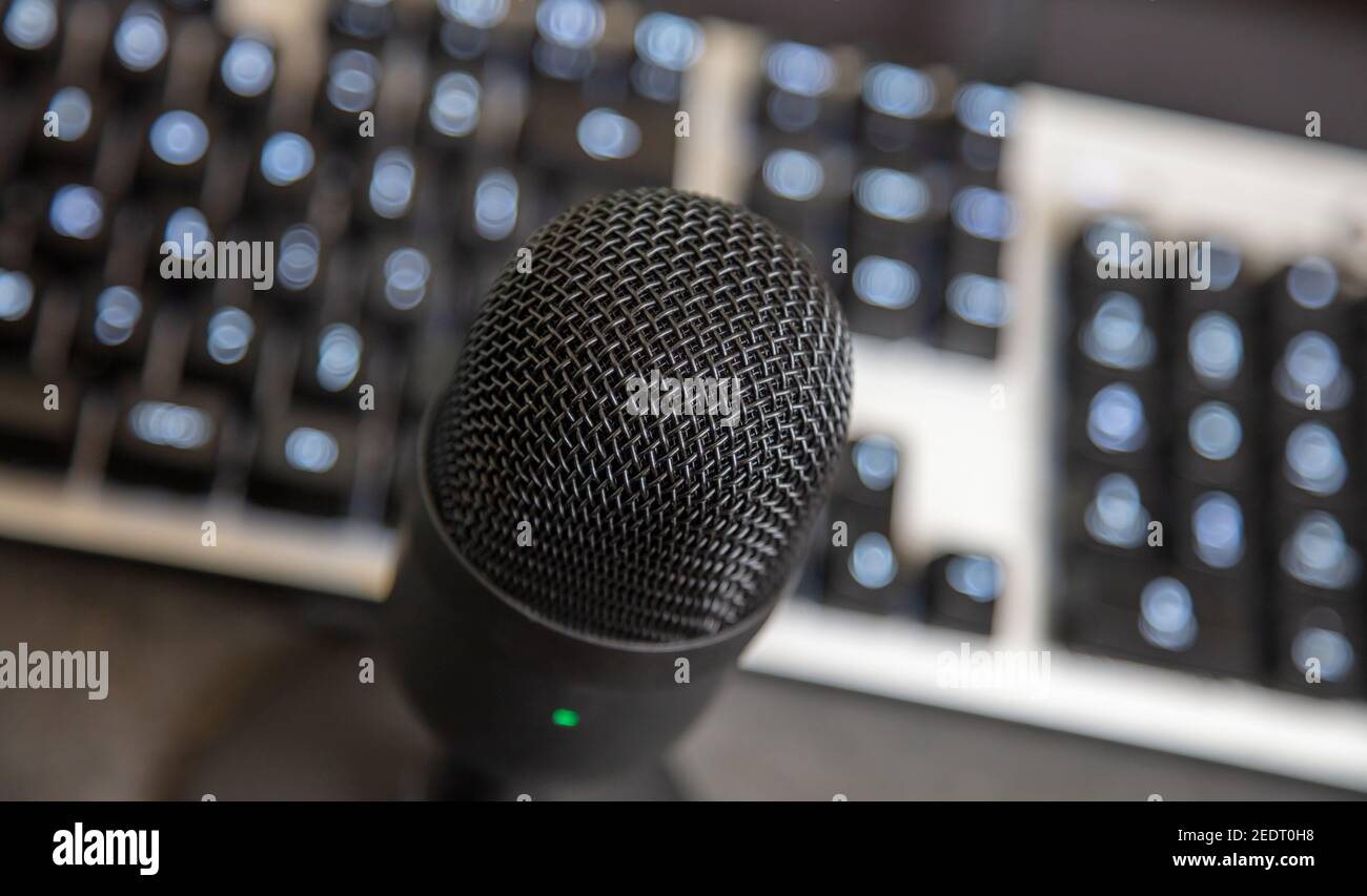 Tilted mike condenser black metallic, blur keyboard background. Digital technology concept. Connection for communication from microphone to pc, record Stock Photo