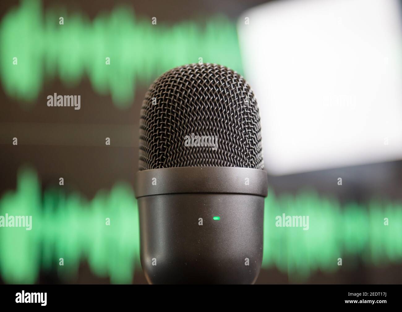 Digital microphone, sound for audience. Mic condenser black metallic, blur green waveform background. Sound recording concept. Mike for live audio, mu Stock Photo