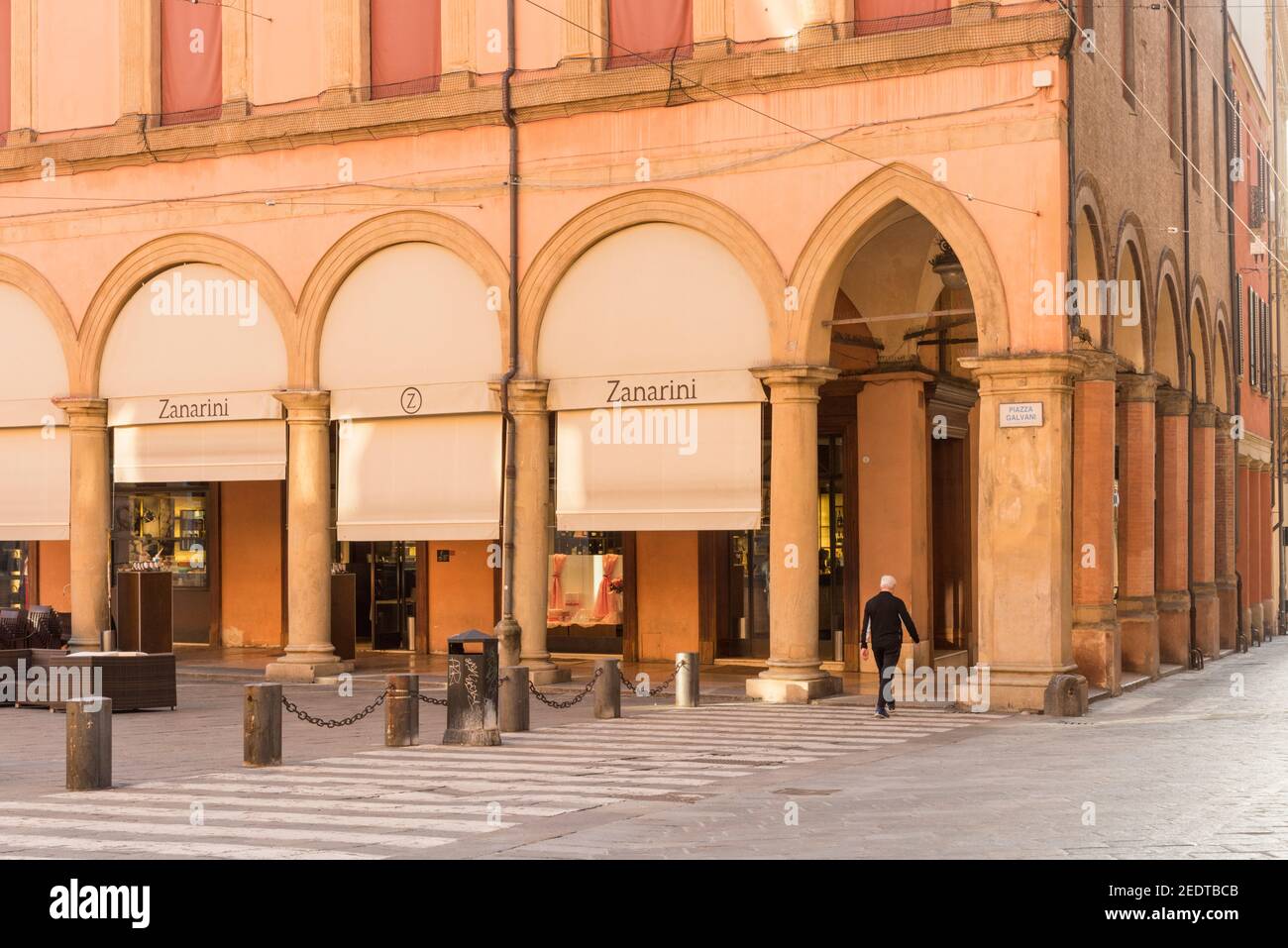 A man crosses a pedestrian crossing in the Piazza Galvani Bologna Italy but the Zanarini cafe Stock Photo