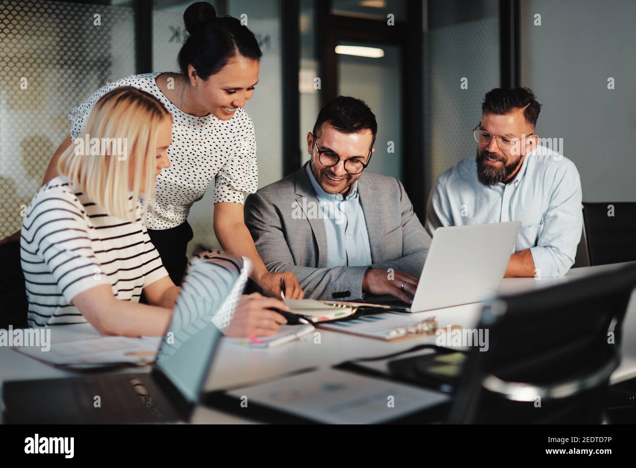 Smiling group of businesspeople talking together at a table during a meeting in an office boardroom Stock Photo