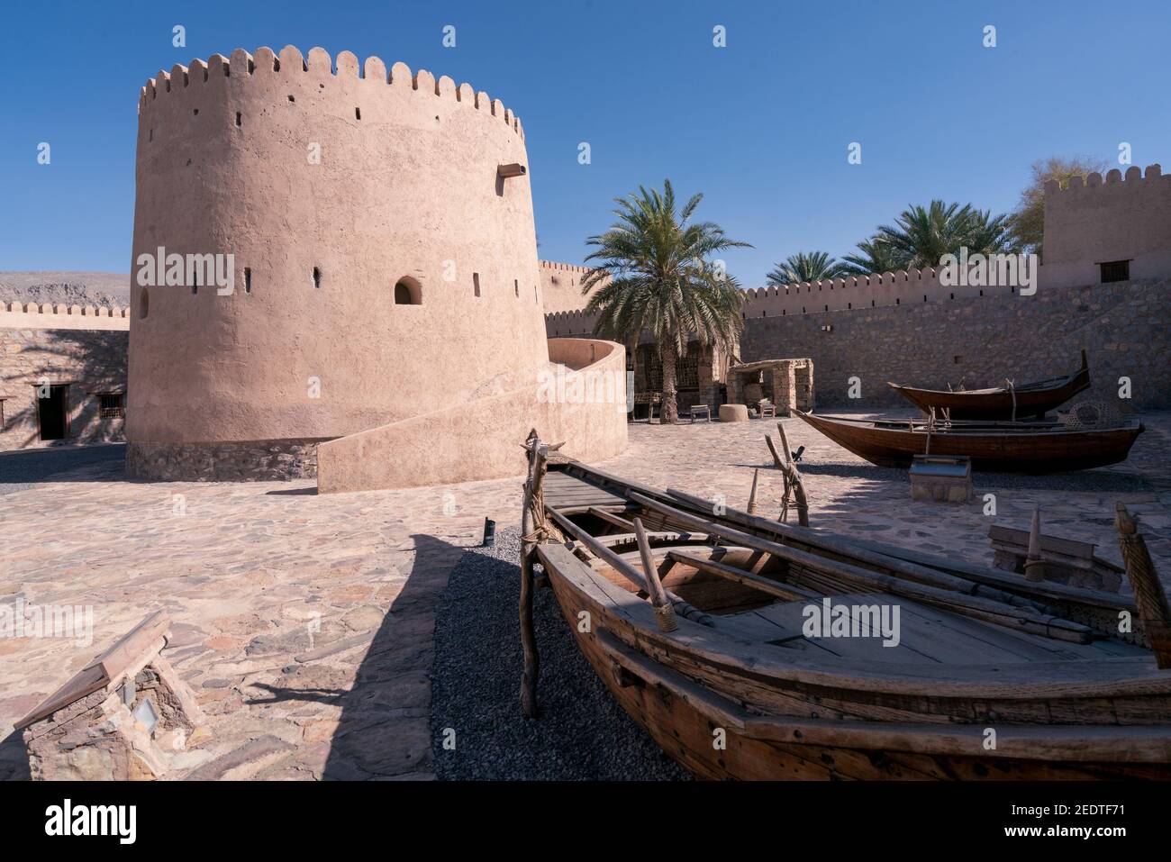 Khasab, Oman - 04.01.2018: Courtyard of medieval arabian fort in Khasab, Oman. Wooden ships exhibition. Stock Photo