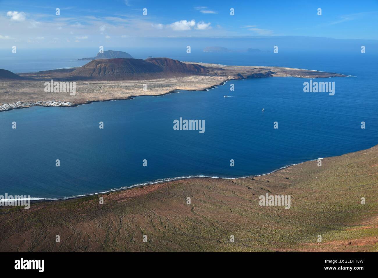 La Graciosa, a small volcanic island in the north of Lanzarote, Spain. Blue ocean and a blue sky with some white clouds. Far in the background the Isl Stock Photo