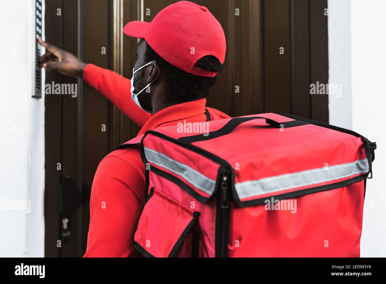 African rider man delivering meal to customers home while wearing face mask during corona virus outbreak - Delivery food concept Stock Photo