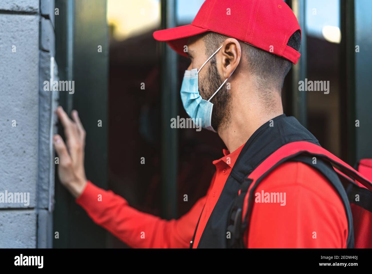 Rider man delivering meal to customers home while wearing face mask during corona virus outbreak - Delivery food concept Stock Photo