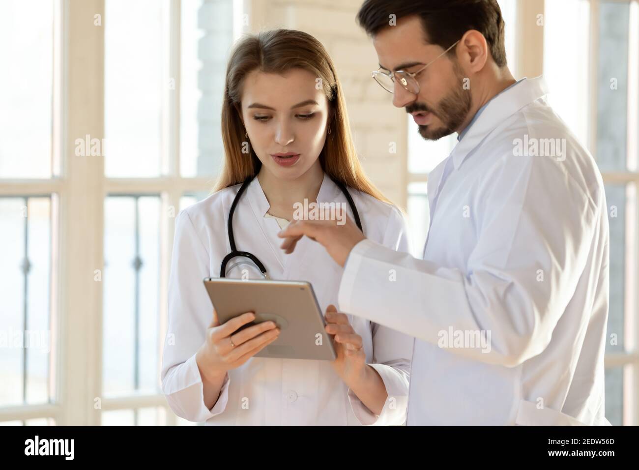Two professional general practitioners colleagues discussing health treatment. Stock Photo