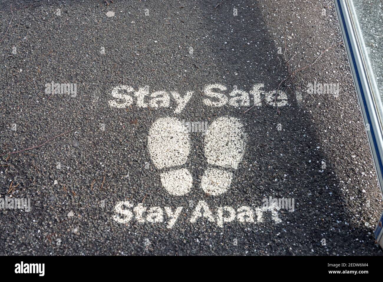 Covid 19 social distancing sign painted on footpath saying stay safe stay apart Stock Photo