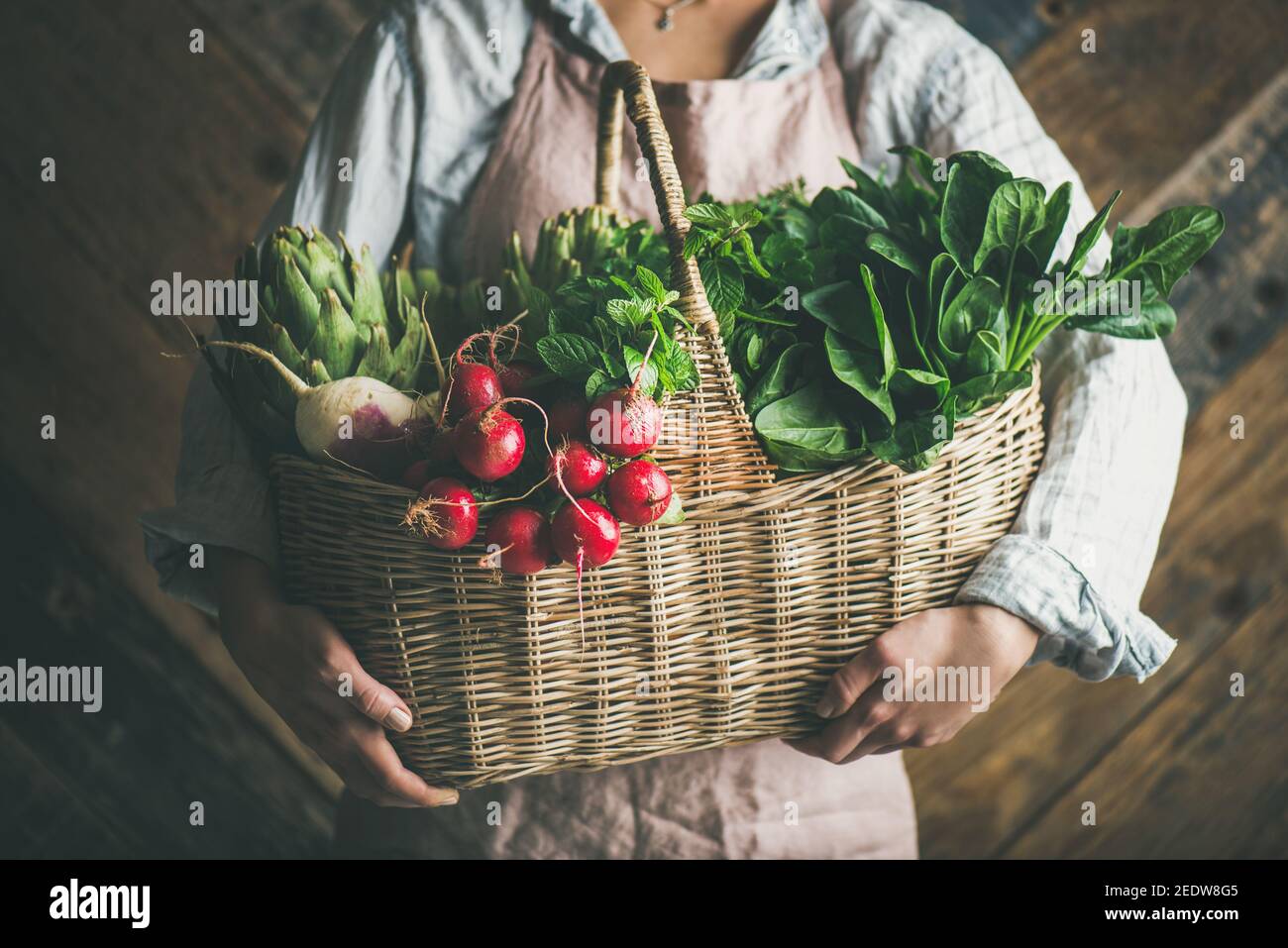 Woman farmer holding basket of fresh organic garden vegetables and ...