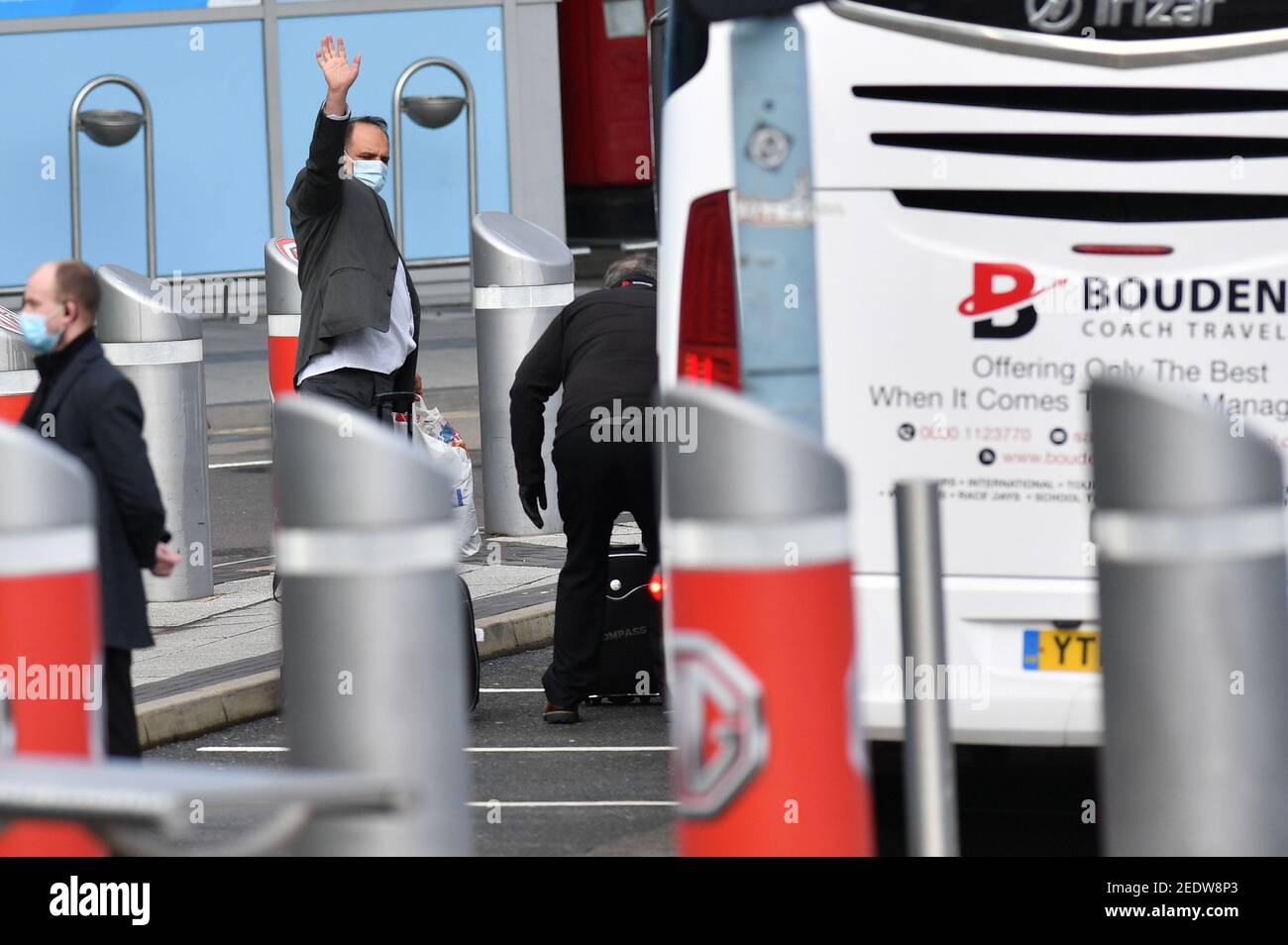 Two passengers leave Birmingham Airport onboard a coach after landing in England. New regulations now in force require anyone who has recently been in a high-risk location to enter England through a designated port and have pre-booked a package to stay at one of the Government's managed quarantine facilities. Picture date: Monday February 15, 2021. Stock Photo